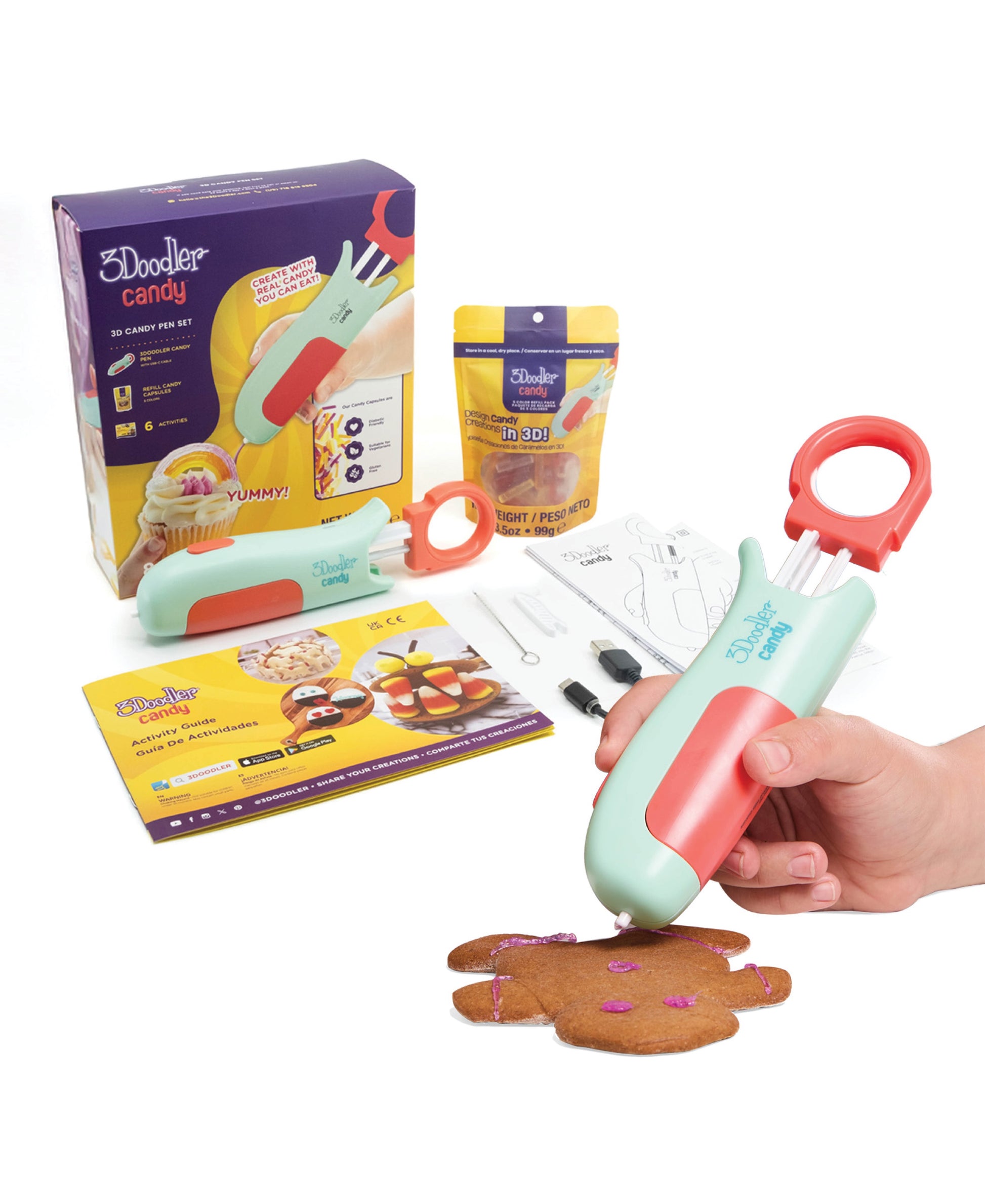 3Doodler Candy 3D Pen Set with mint-green and coral pen, refill cartridges, activity guide, and gingerbread cookie decorated with purple candy dots, modeled by