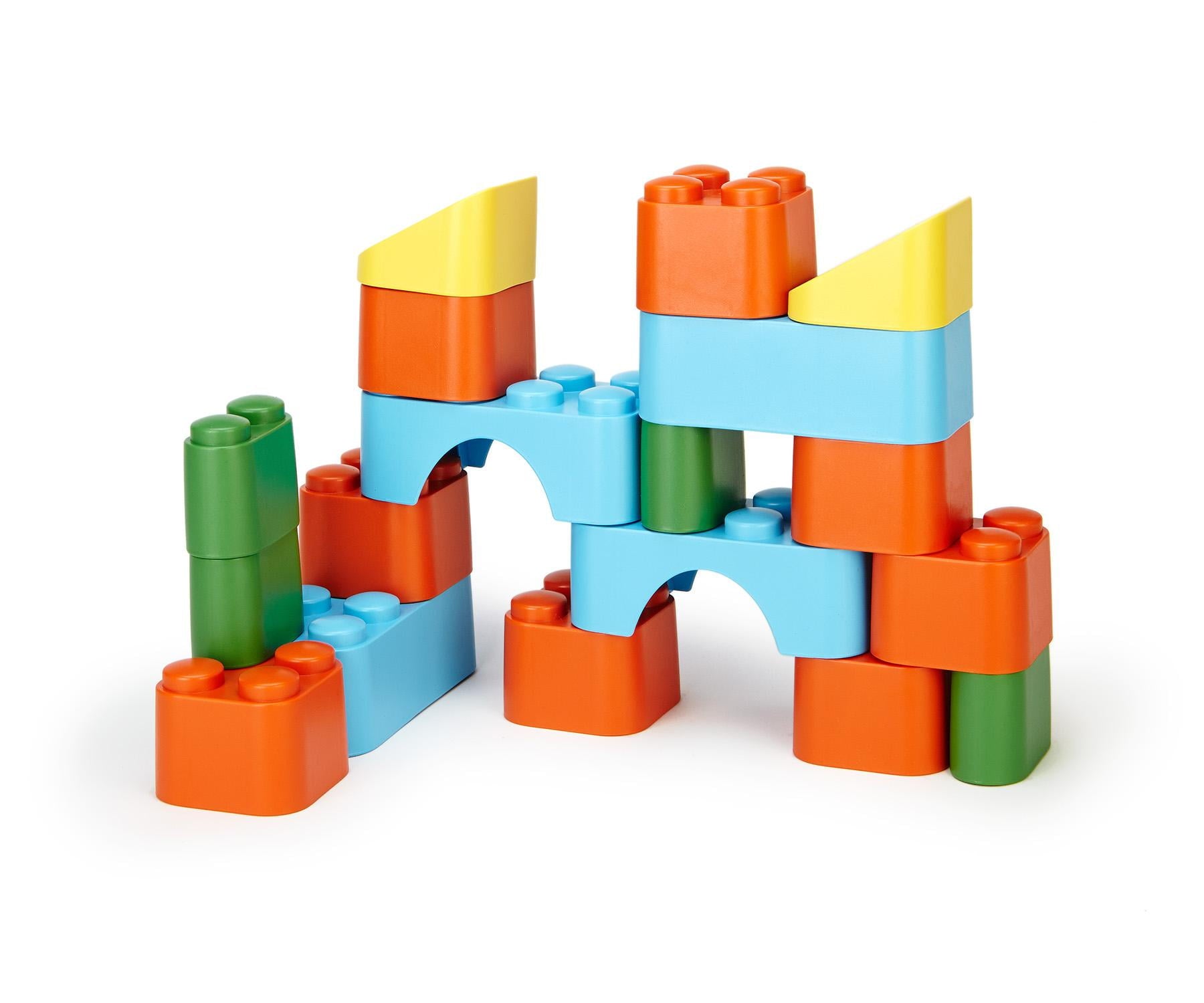 Colorful building blocks set with orange, blue, green, and yellow pieces stacked into a castle-like structure on white background