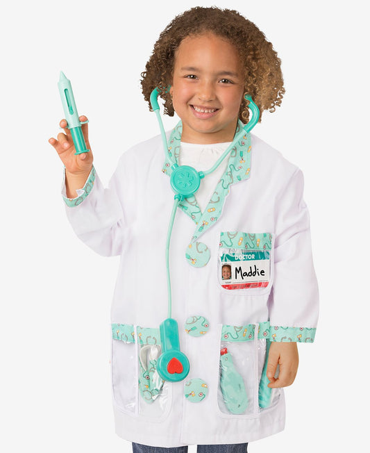 Child modeled by a child wearing white doctor coat with turquoise stethoscope, name badge, and medical accessories, holding turquoise syringe toy