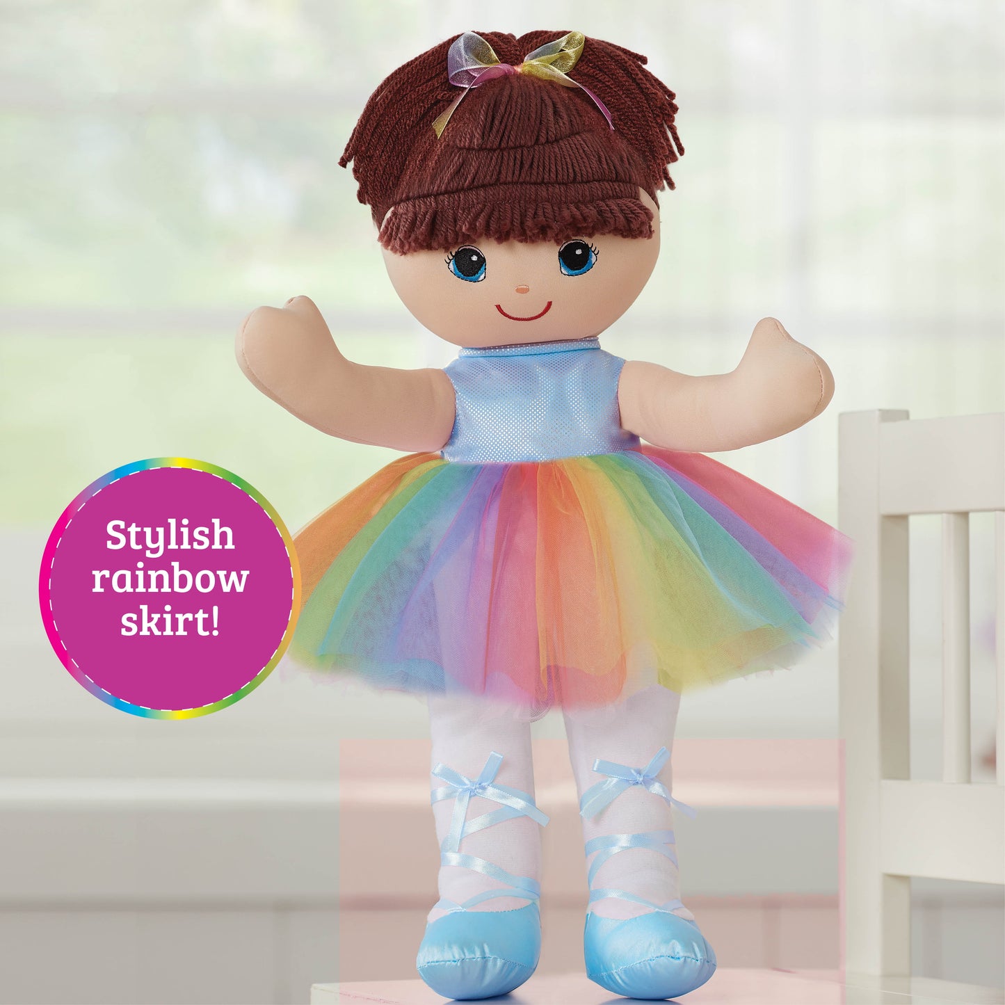 Soft doll with dark red hair and blue eyes, wearing lavender top, rainbow tulle skirt, white socks with blue ribbon bows, and blue shoes