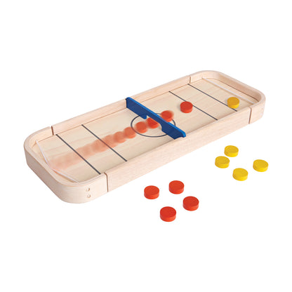 Wooden 2-in-1 shuffleboard and disc-flicking board game with blue pusher, red and yellow game pieces on plain background