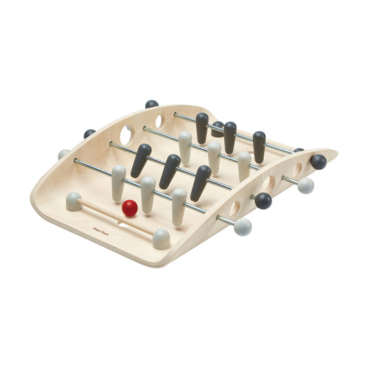 Wooden tabletop foosball game with light natural wood frame, metal rods, and black, white, and gray player pieces with one red ball
