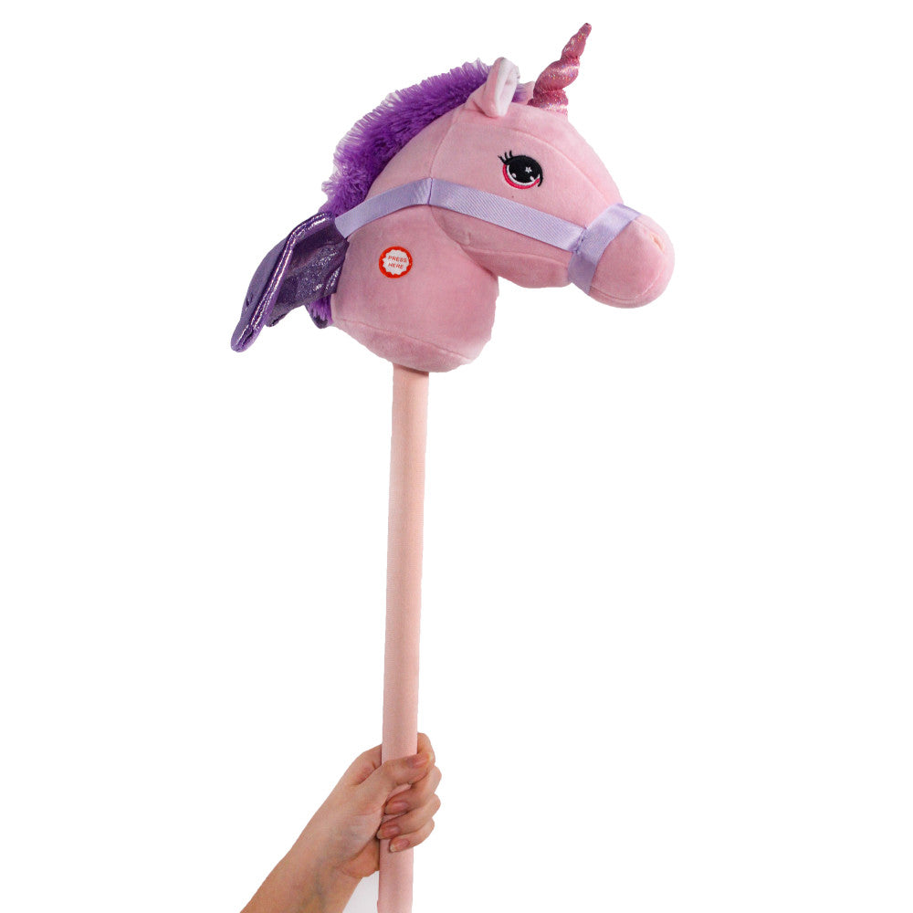 Pink plush unicorn stick horse with purple mane and glittery pink horn, modeled by a child holding the wooden dowel handle