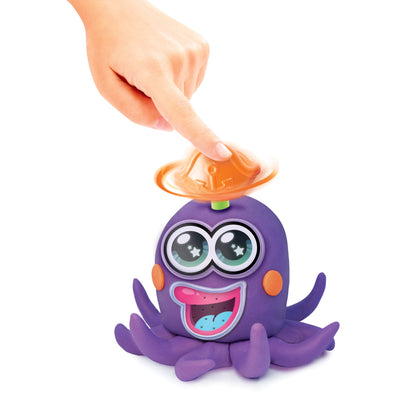 Child's hand pressing orange UFO-shaped tool onto purple octopus character with big eyes and open mouth, modeled by a child