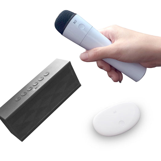 Moxxi Go Karaoke wireless singing system with white microphone held in hand, gray speaker with control buttons, and white carrying case on plain background