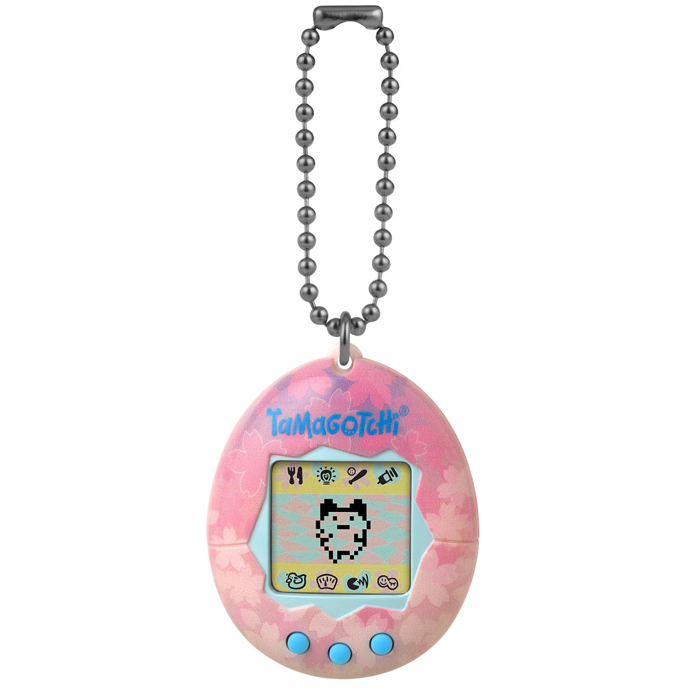Pink Tamagotchi Original Sakura Edition digital pet with cherry blossom pattern, pixel character display, game icons, three blue buttons, and metal ball chain k
