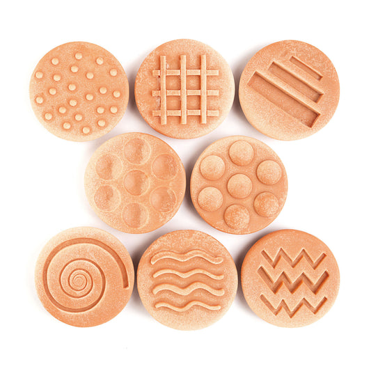 Eight terracotta-colored textured stones with embossed patterns including dots, grid, lines, circles, spiral, and wavy designs
