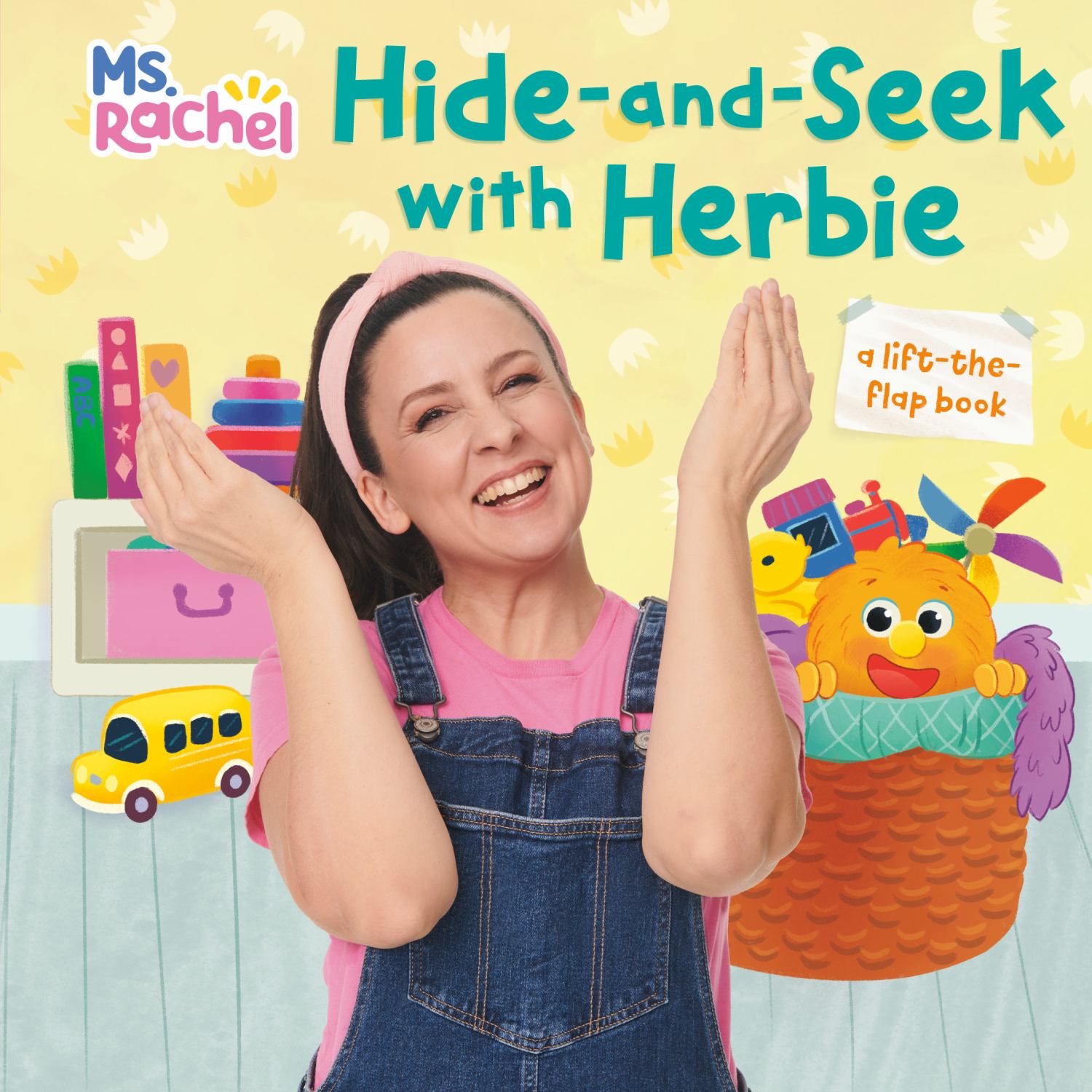 Ms. Rachel Hide-and-Seek with Herbie a lift-the-flap book, modeled by a child with toys including a yellow bus and orange character in basket