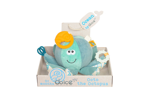 Turquoise plush octopus with smiling face, yellow teether ring, white rattle ring, and patterned tentacles, displayed in branded box