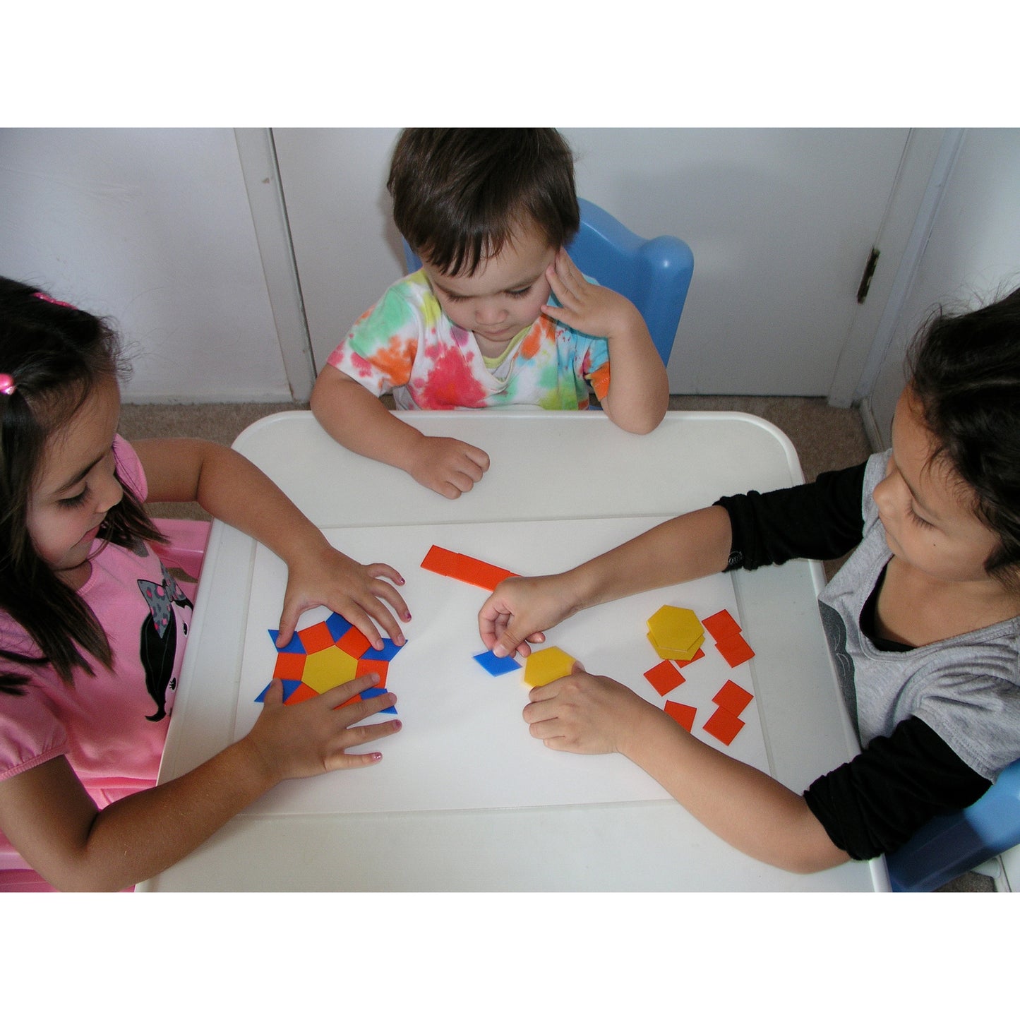 EduStic Pattern Smart Game with colorful geometric shapes in red, blue, and yellow being arranged by children