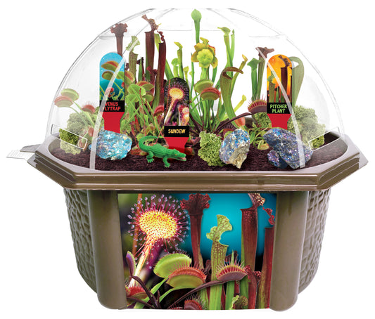 Carnivorous plant terrarium kit with clear dome habitat containing Venus flytrap, sundew, and pitcher plant with labeled specimens and decorative rocks on tan b