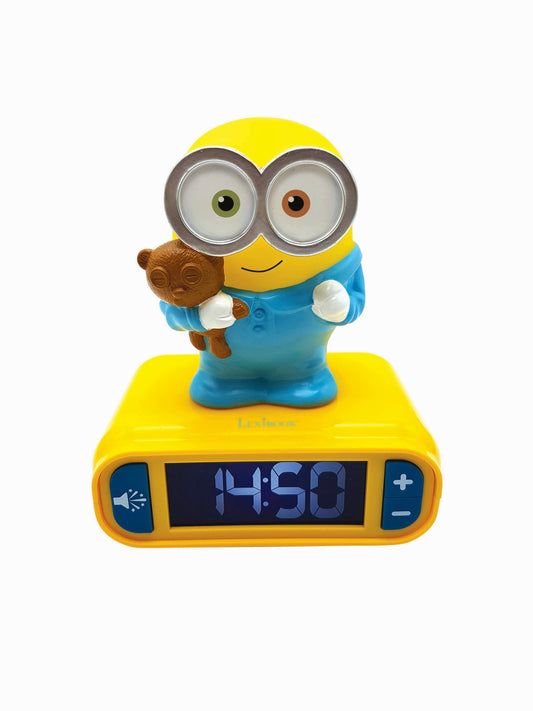 Yellow Minion character alarm clock with large eyes, blue overalls, holding small teddy bear, digital display showing 4:50, yellow base with controls