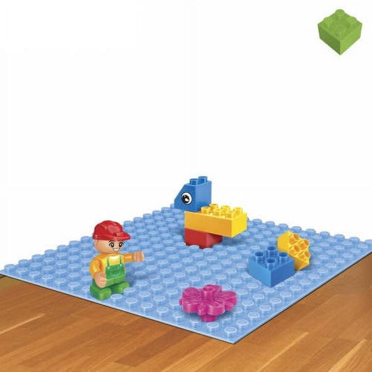 Blue building block baseplate with colorful bricks, minifigure in red hat, blue bird figure, and pink flower piece on wooden surface
