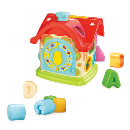 Colorful plastic learning house with red roof, blue door with yellow center, green base, and shape-sorting pieces including cylinder, cube, and triangle blocks