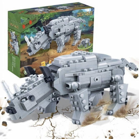 Gray brick building set assembled into a rhinoceros figure on cracked white ground with scattered rocks, shown with original packaging box in background