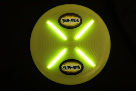 Lumi-niter yellow glow disc with bright green LED lights forming an X pattern, displayed against black background