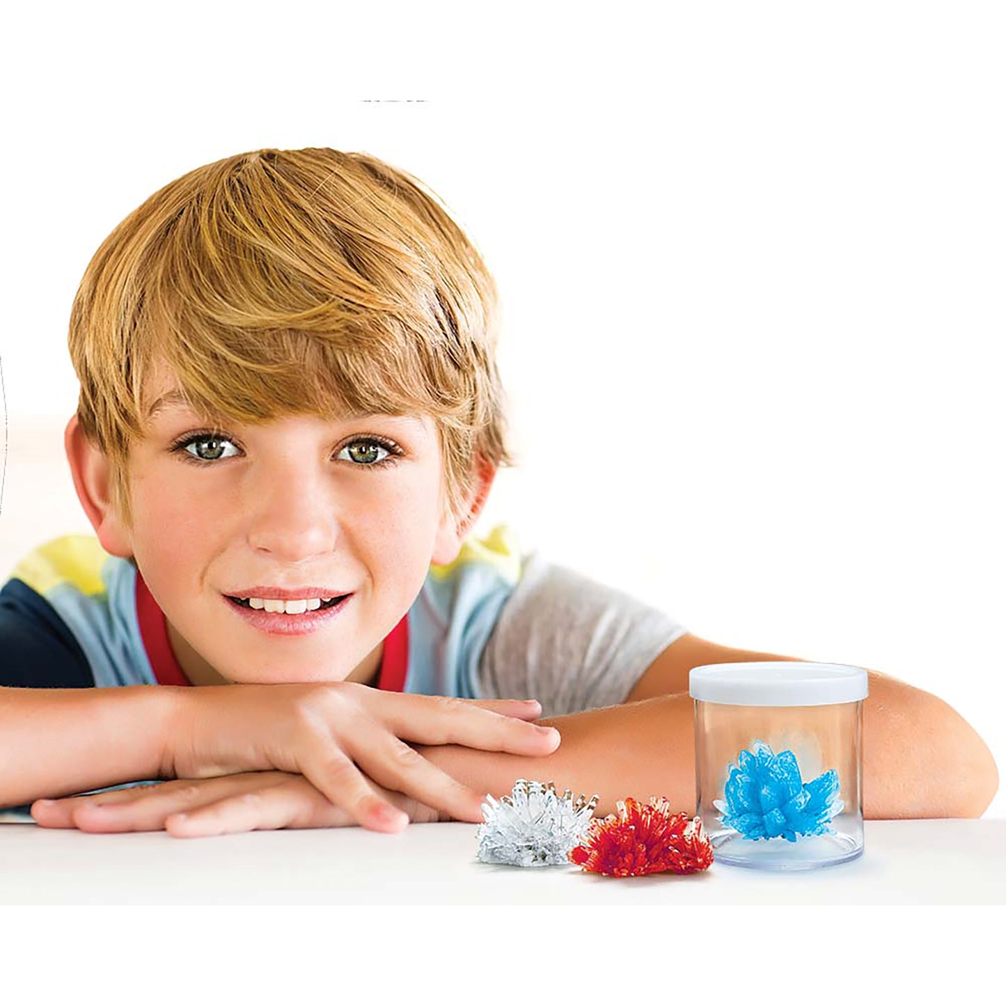 4M Crystal Growing Kit with boy displaying three colored crystals in red, white, and blue