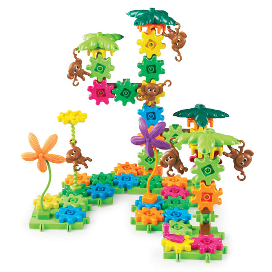 Colorful gear-building set with interlocking plastic gears in multiple colors, leaf-shaped canopies, small brown monkey figures with hooks, and a green base pla