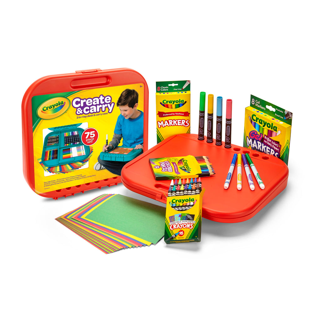 Crayola Create & Carry case with red hinged desk and carrying handle, displayed open with markers, colored pencils, crayons, and colored paper sheets, modeled b