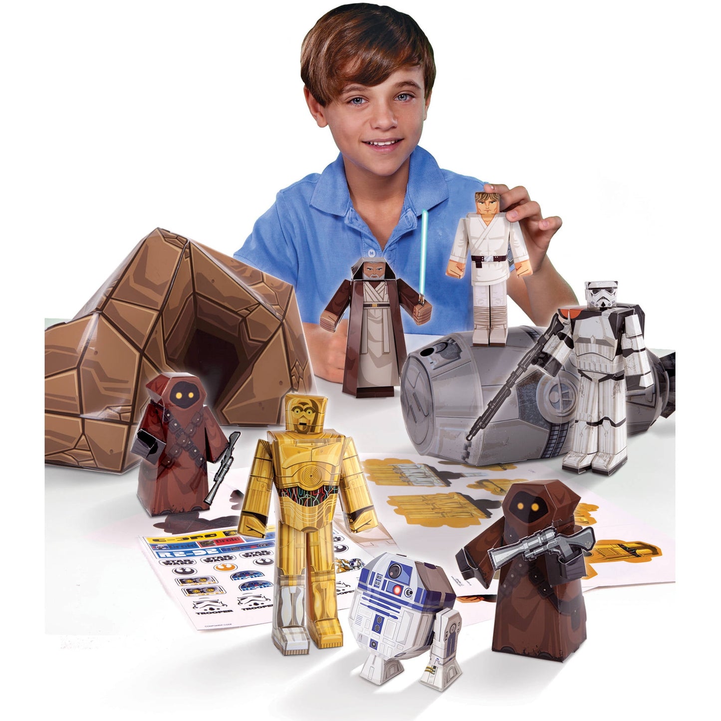Child modeled by a boy in blue shirt displaying Star Wars Tatooine Droid Builder paper craft kit with assembled cardboard figures including C-3PO, R2-D2, Jedi,