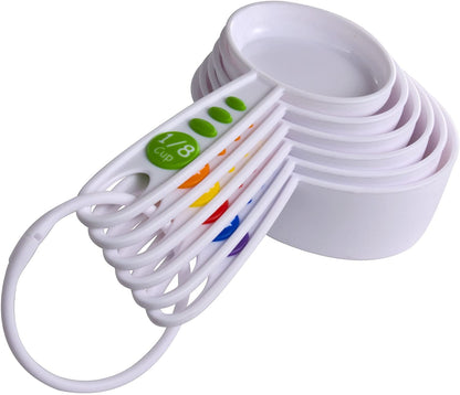 Set of eight white measuring cups with colored handles and green 1/8 cup label, stacked and fanned to show range