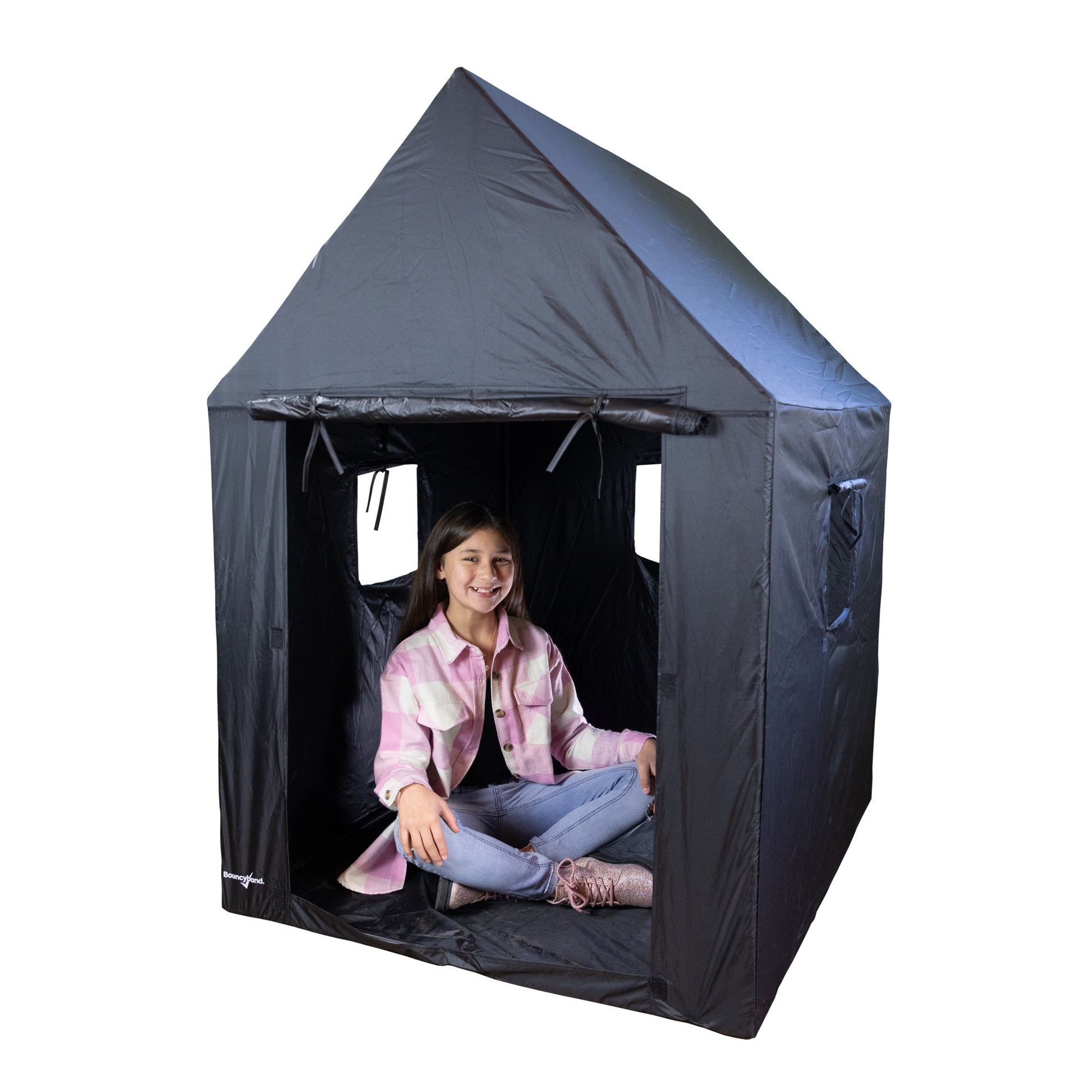Child sitting inside dark den tent with peaked roof and open front windows, modeled by a child wearing pink plaid shirt