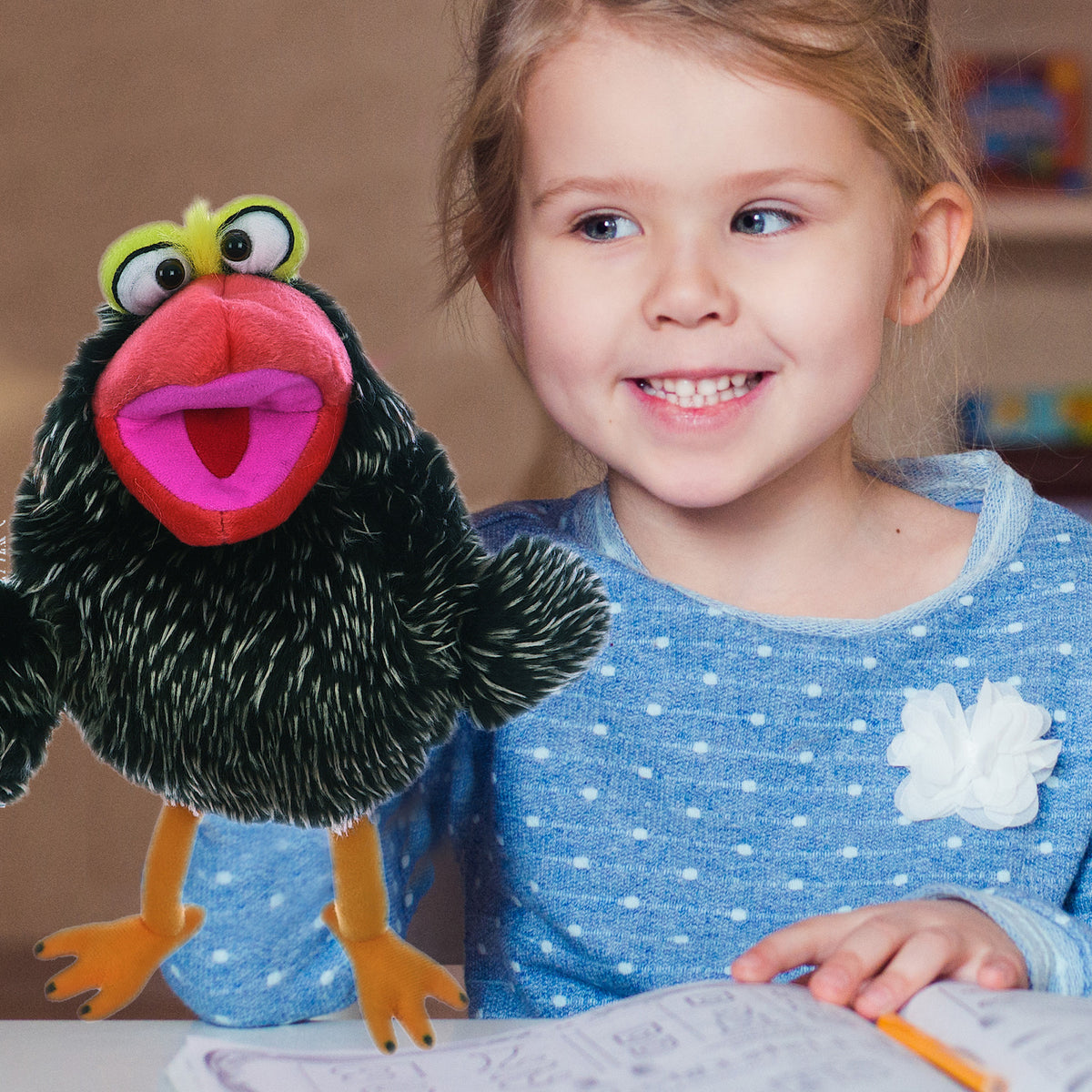 Living Puppets: Poe The Bird hand puppet with black body, red mouth, yellow eyes, and orange feet, held by smiling child