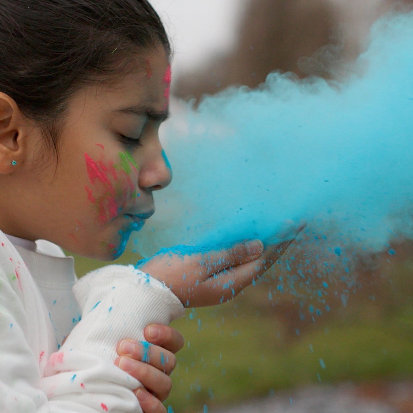 Holi Color Powder 7-pack showing vibrant blue, pink, and green powder being blown by person
