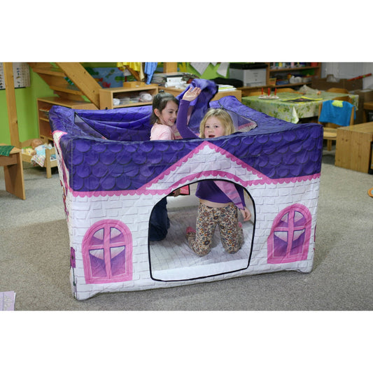 Purple and pink inflatable playhouse with white brick design and arched doorways, modeled by two children inside a classroom setting