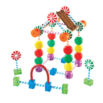 Candy-themed building set with colorful beads, striped connectors, peppermint lollipops, chocolate bar piece, and green base blocks forming an abstract structur