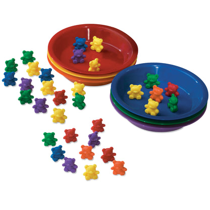 Colorful plastic bear counters in red, yellow, blue, green, purple, and orange arranged around three nesting bowls in red, blue, and purple