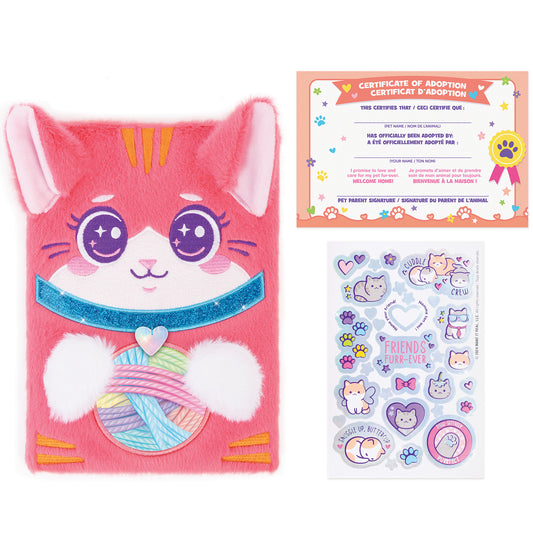 Pink plush cat adoption journal with purple embroidered face, sparkly blue mouth, colorful yarn ball detail, adoption certificate, and sticker sheet