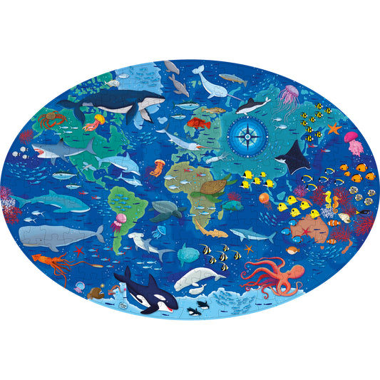 Oval-shaped puzzle featuring an underwater ocean scene with whales, sharks, sea turtles, coral, jellyfish, tropical fish, octopus, and a compass rose on a blue