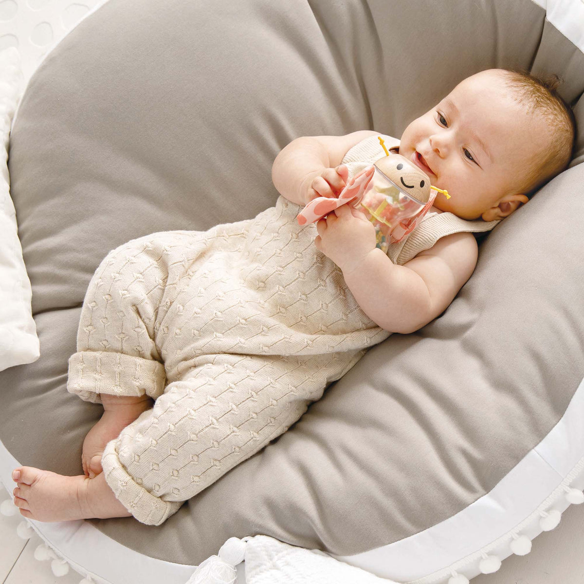 Butterfly Rainmaker Robert soft toy in cream with pink details, held by baby