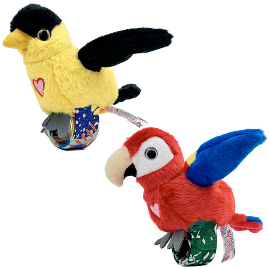 Two plush bird toys: yellow bird with black cap and wings, pink heart on chest; red macaw with blue wings and white face patch, pink heart on chest