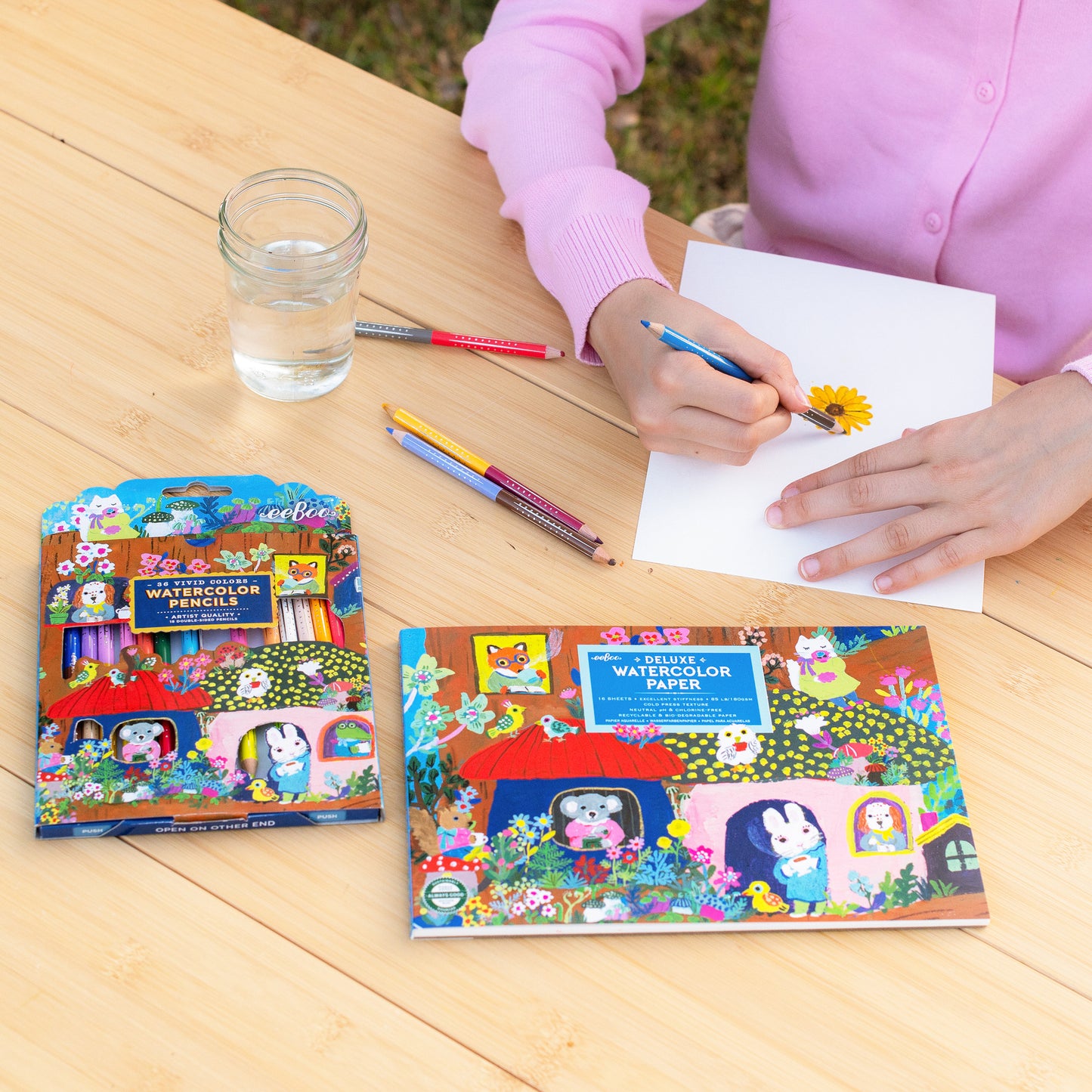 Deluxe Watercolor Paper Pad with colorful floral design, shown with watercolor pencils and child drawing