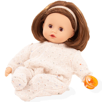 Muffin Doll 13" soft doll with brown hair, headband, beige knit jumpsuit, holding orange pacifier