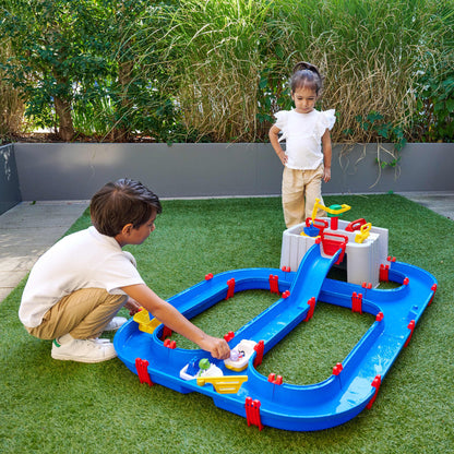 AquaPlay Harbor water table toy with blue channels, red gates, and accessories on artificial grass
