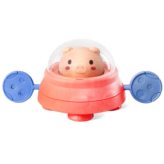 Pink pig character with closed dome top and blue planetary wheels on sides, bath toy on plain background