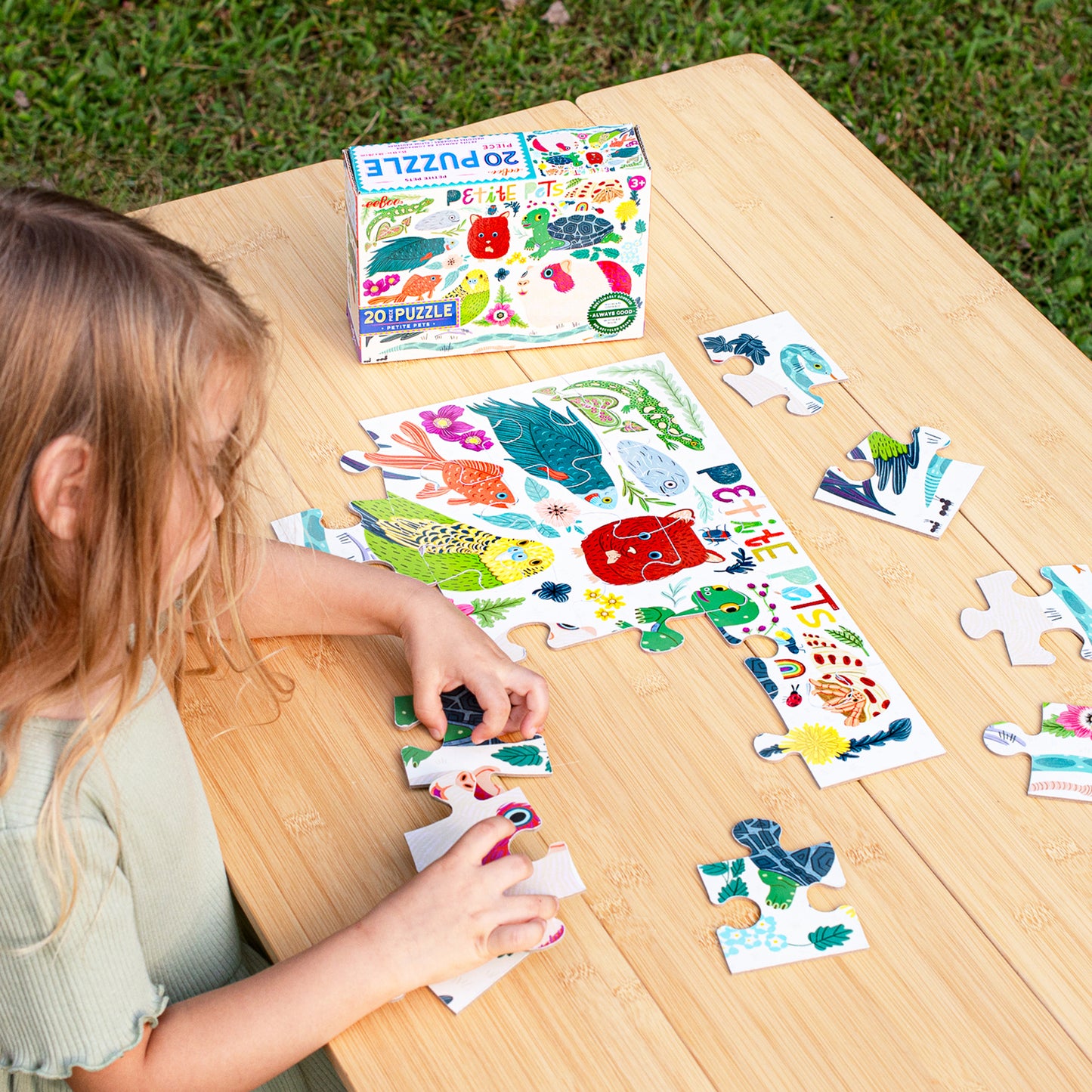 20 Piece Puzzle Petite Pets with colorful fish and animal designs, child playing with puzzle pieces on wooden table