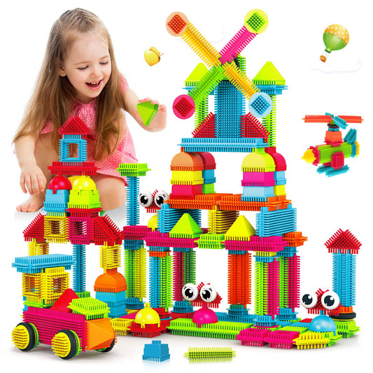 Child modeled playing with colorful bristle building blocks assembled into a multi-story castle structure with towers, domes, and decorative shapes in red, yell