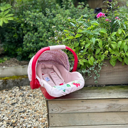 Roma RHS Flora pink doll car seat with hood and harness in garden setting
