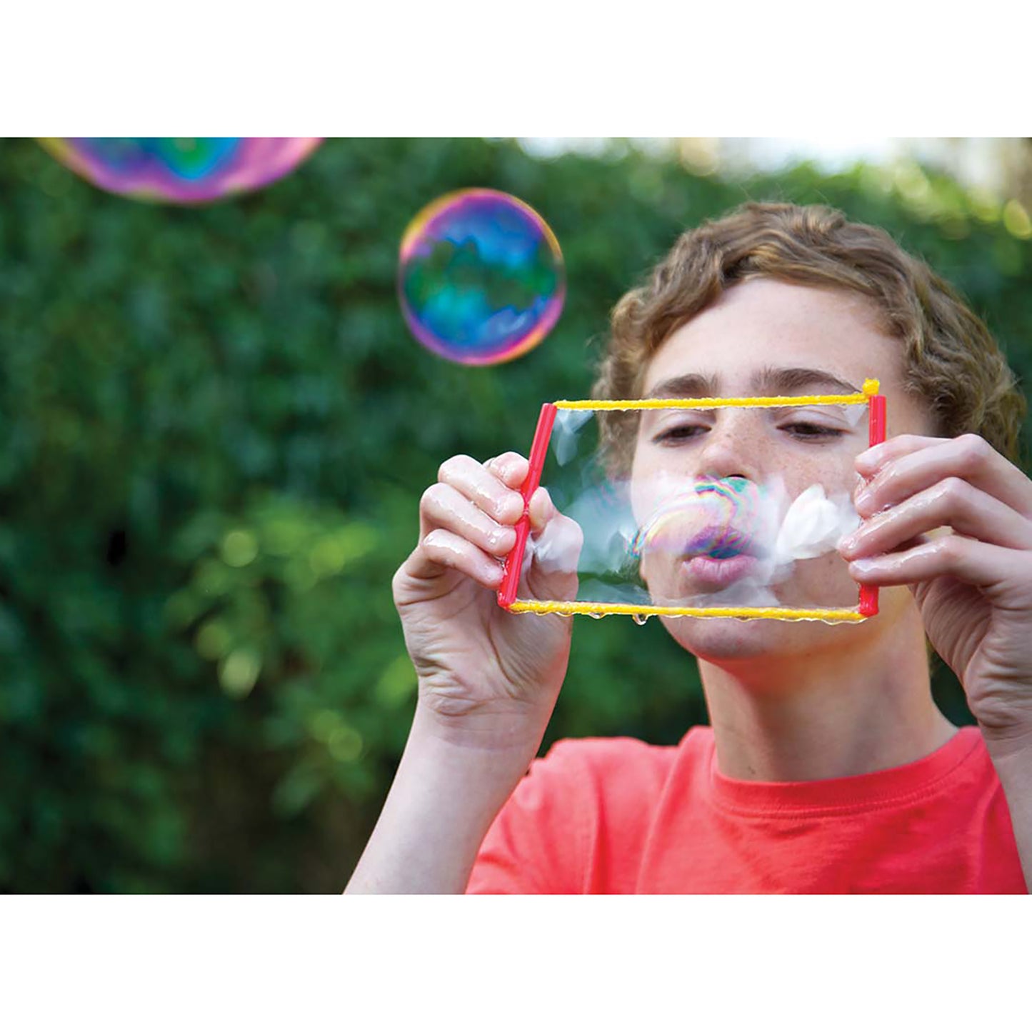 KidzLabs Bubble Science kit with red wand creating colorful bubbles outdoors