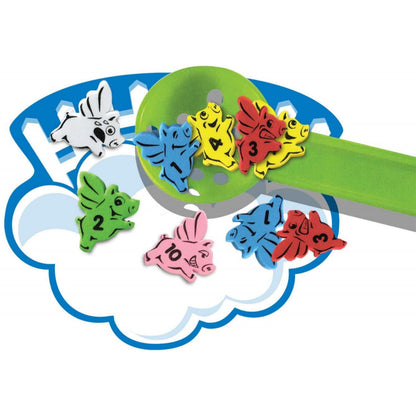 When Pigs Fly! Family Action Game showing colorful numbered pig pieces on a cloud-shaped board with a green ramp