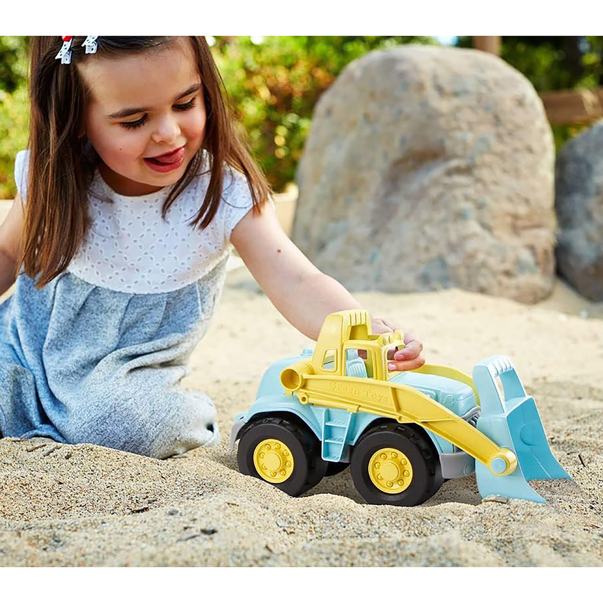 Blue and yellow loader truck toy in sand with child playing