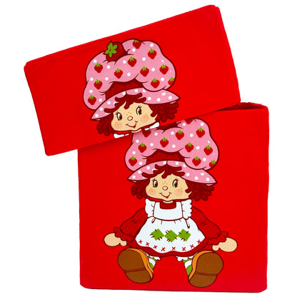 Red fabric storage bin featuring two Strawberry Shortcake dolls with pink strawberry-patterned hats, red curly hair, and white dress with green tree design