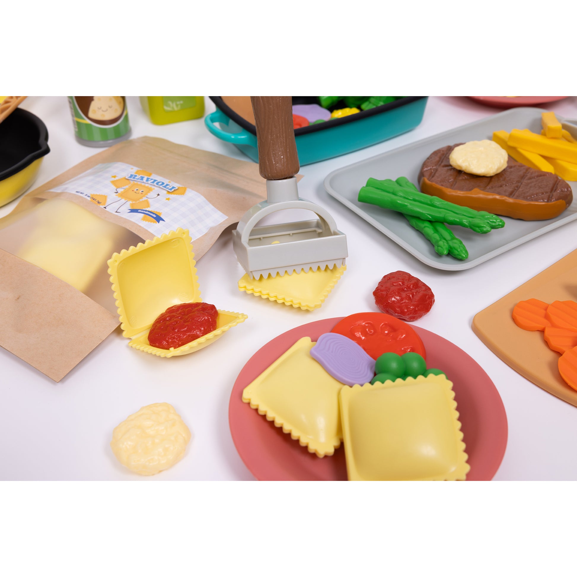 Ravioli Cooking Set with pretend play food pieces including yellow pasta, red tomato sauce, purple eggplant, green beans, and pasta-making tools on plates and c
