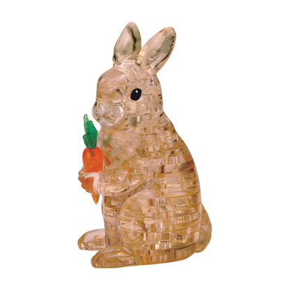 Transparent amber crystal bunny puzzle holding a small carrot, assembled 3D puzzle piece set on plain white background