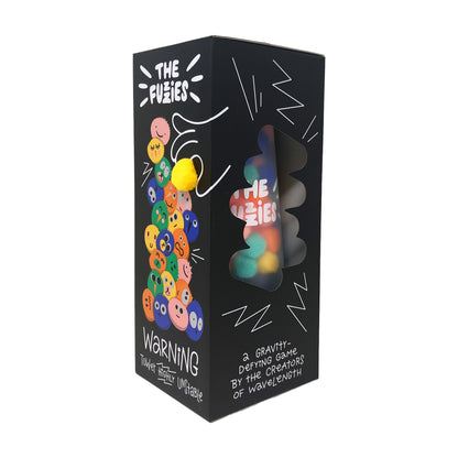 The Fuzzies Colorful Tower Stacking Family Game box showing stacked fuzzy ball characters and gravity-defying game pieces visible through window