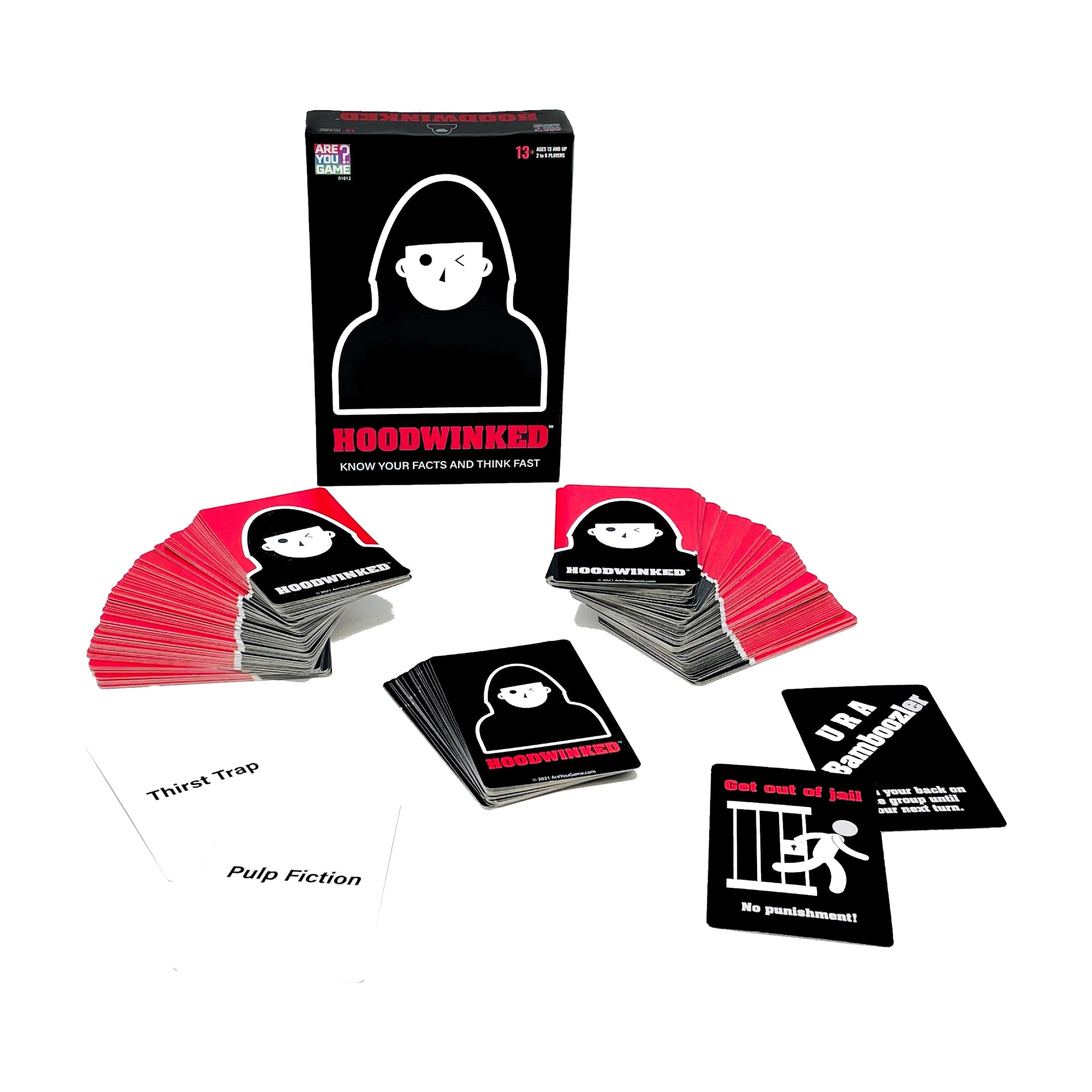 Hoodwinked card game box and contents displayed, showing black game box with white hooded figure icon, stacks of pink and black cards fanned out, and sample car